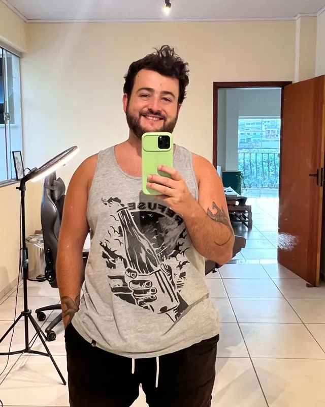 Aluno antes, de regata cinza em frente ao espelho