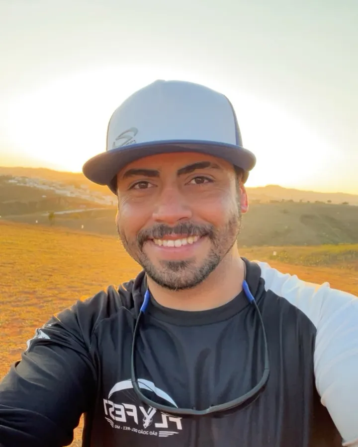 Igor sorrindo ao ar livre, ao pôr do sol